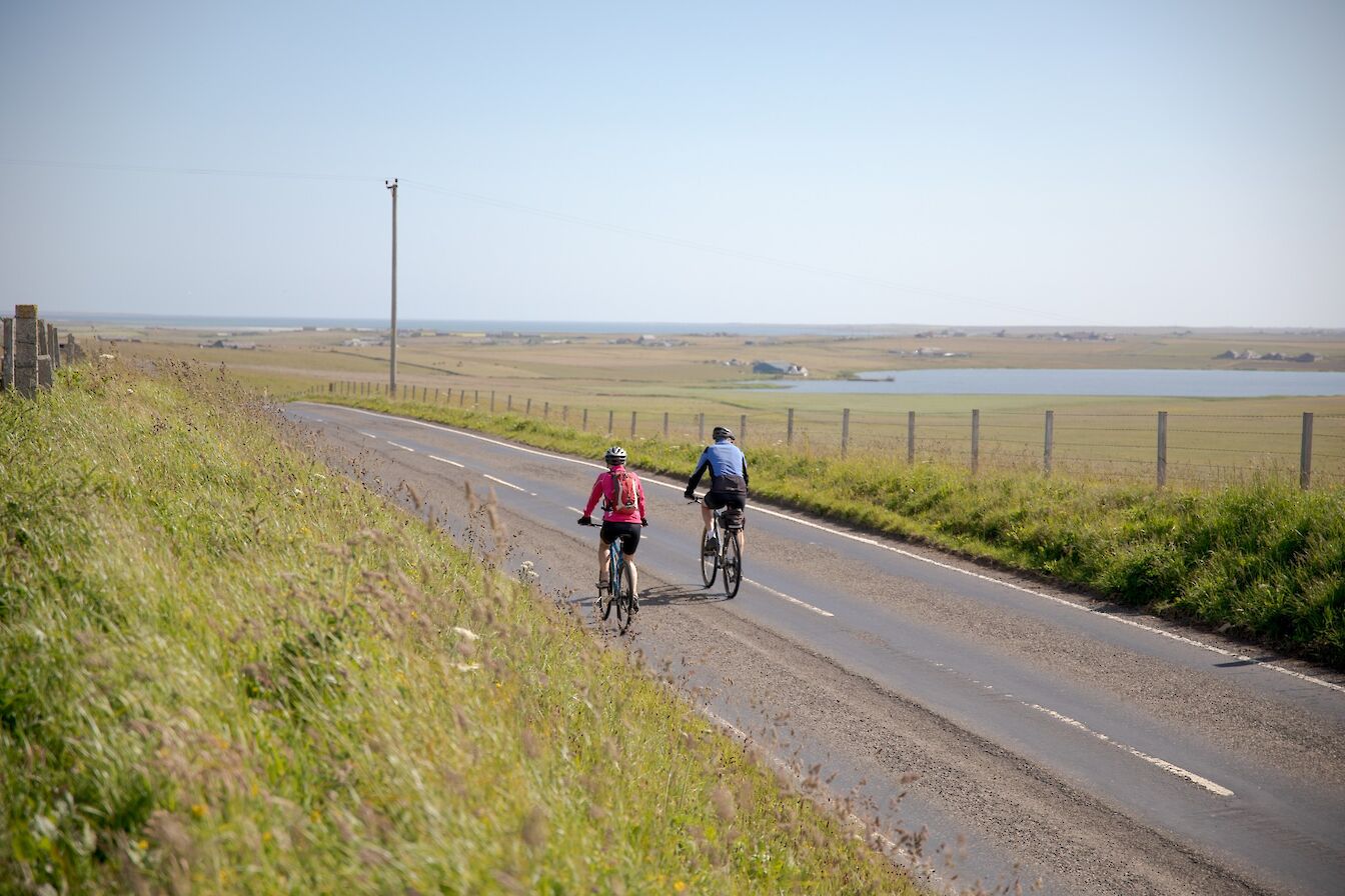 Cyclists on the main Sanday road, Sanday, Orkney